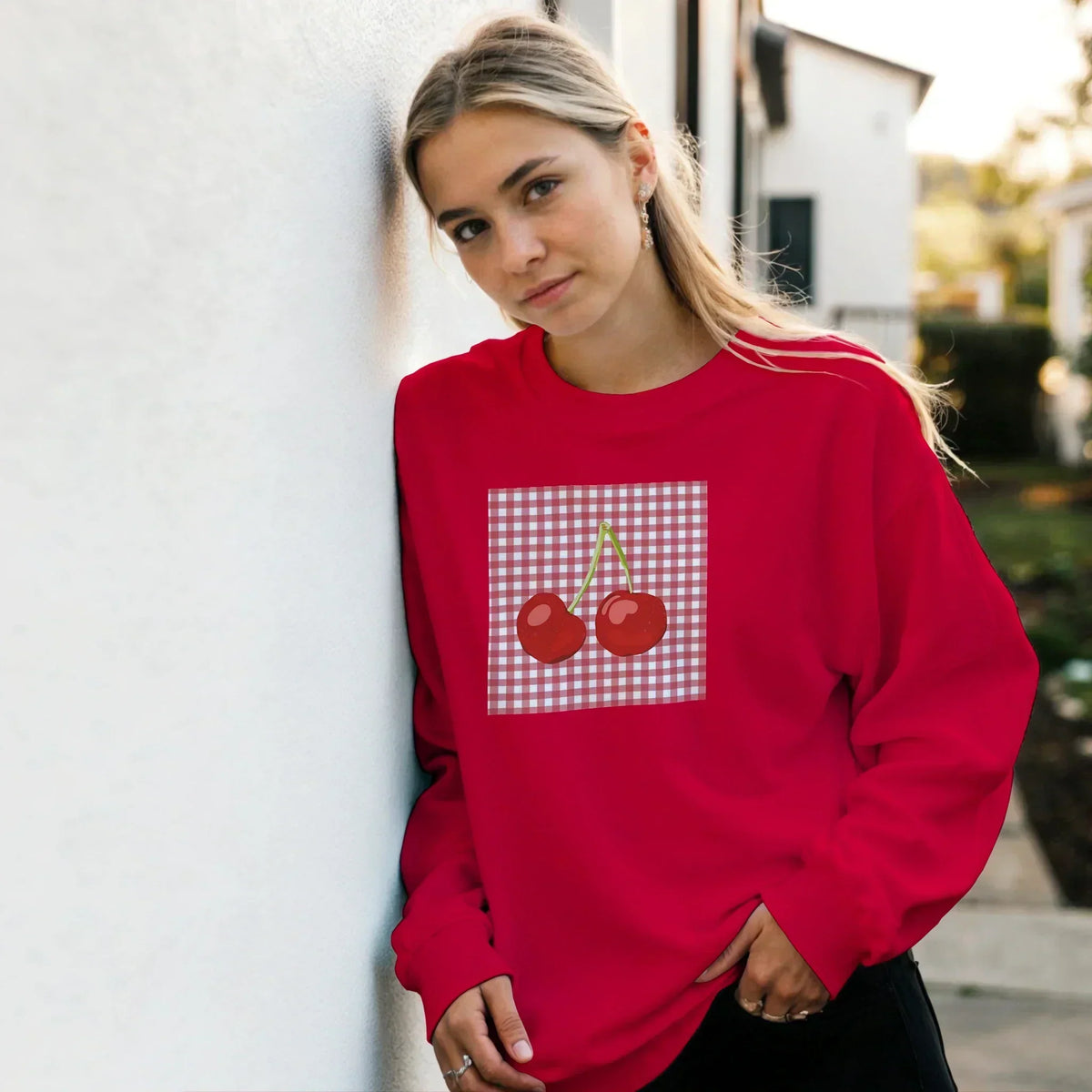 Woman wearing a red sweatshirt with a cherry gingham graphic design