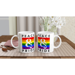 Two white mugs featuring rainbow 'PEACE & PRIDE' design on a table.