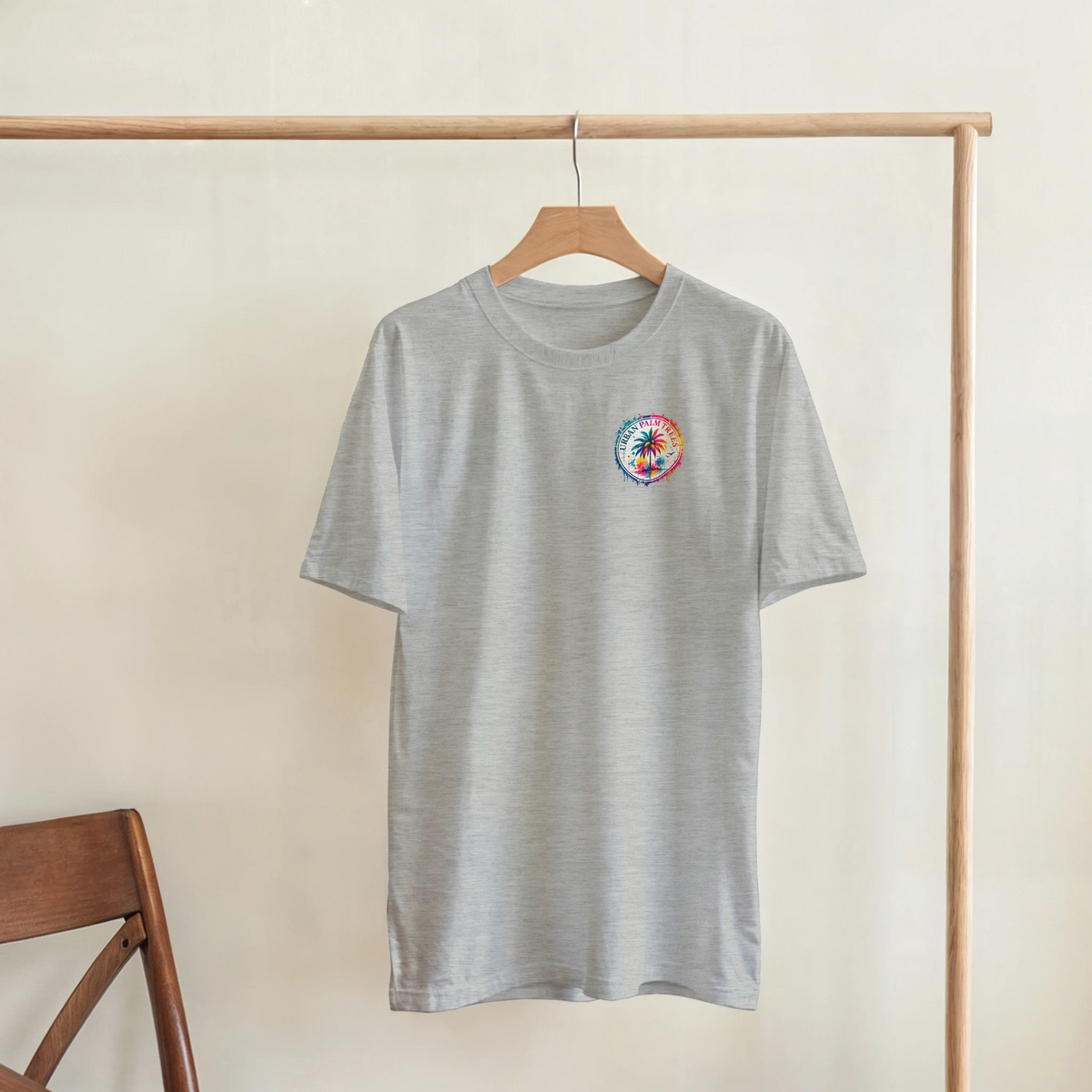 Heather grey t-shirt hanging on a rack with a small, colorful circular Urban Palm Trees graphic on the left chest.