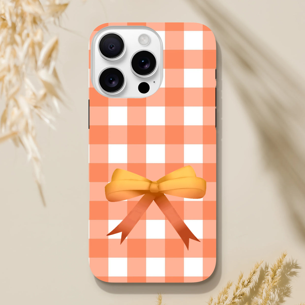 Orange gingham iPhone case with a 3D ribbon bow. Cute coquette tough cover with impact-resistant shielding for daily commutes.