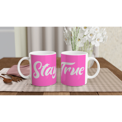 Two pink Stay True mugs with white cursive slogans on a wooden table.