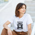 Woman wearing white Tropical Paradise women's graphic T-shirt with a black portrait and tropical leaves.