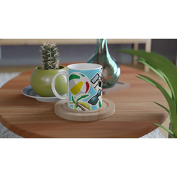Summer holiday ceramic mug featuring beach ball, palm tree, sunglasses, and camera print on a wooden table.