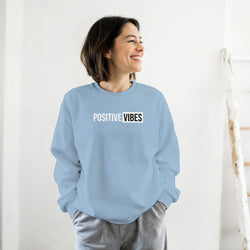 Woman wearing a light blue sweatshirt with the 'POSITIVE VIBES' slogan, casual streetwear look.