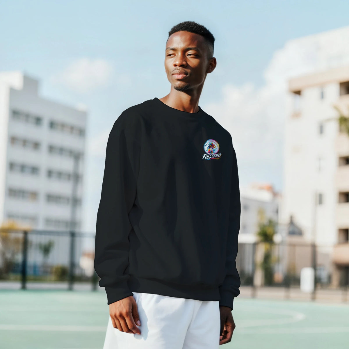 Model wears black Full Send sweatshirt with colorful tropical logo on chest, showcasing streetwear style outdoors.