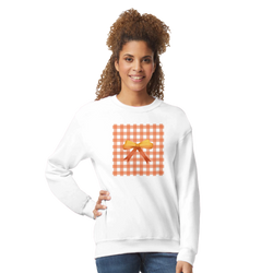 Woman wearing white sweatshirt with orange gingham square and bow detail.