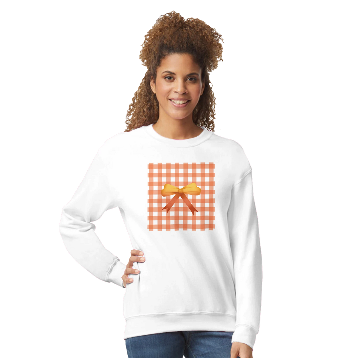 Woman wearing white sweatshirt with orange gingham square and bow detail.
