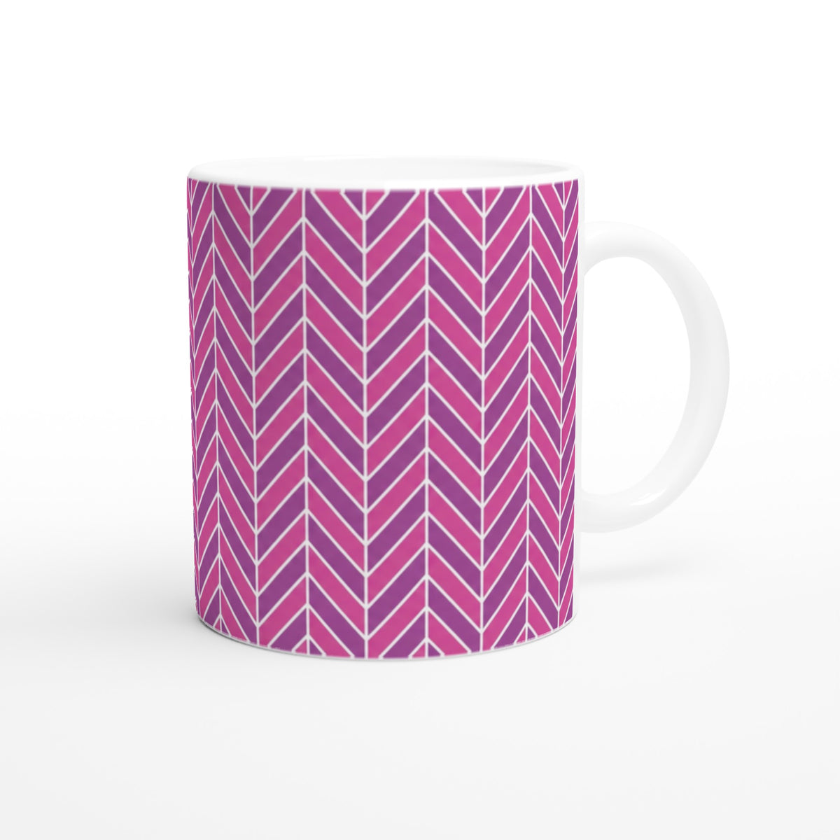Pink herringbone ceramic mug featuring a bold retro geometric chevron pattern in shades of pink and purple with a smooth white handle.