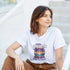 Woman wearing a white Mai Tai Dreams graphic T-shirt featuring tropical palm trees and a sunset.