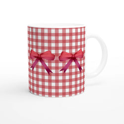 Red gingham bow mug with pink ribbons around its ceramic body and a white handle.