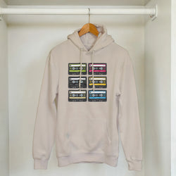 Beige pullover hoodie featuring a grid of six colorful retro cassette tapes on the chest, capturing vintage 90s music nostalgia.