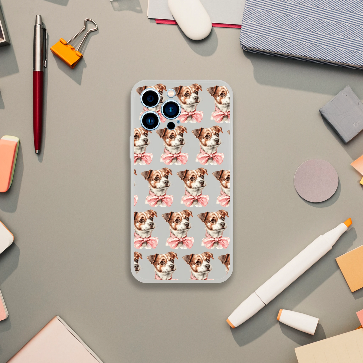 Clear iPhone case with a repeating pattern of brown-and-white puppies wearing pink bows.