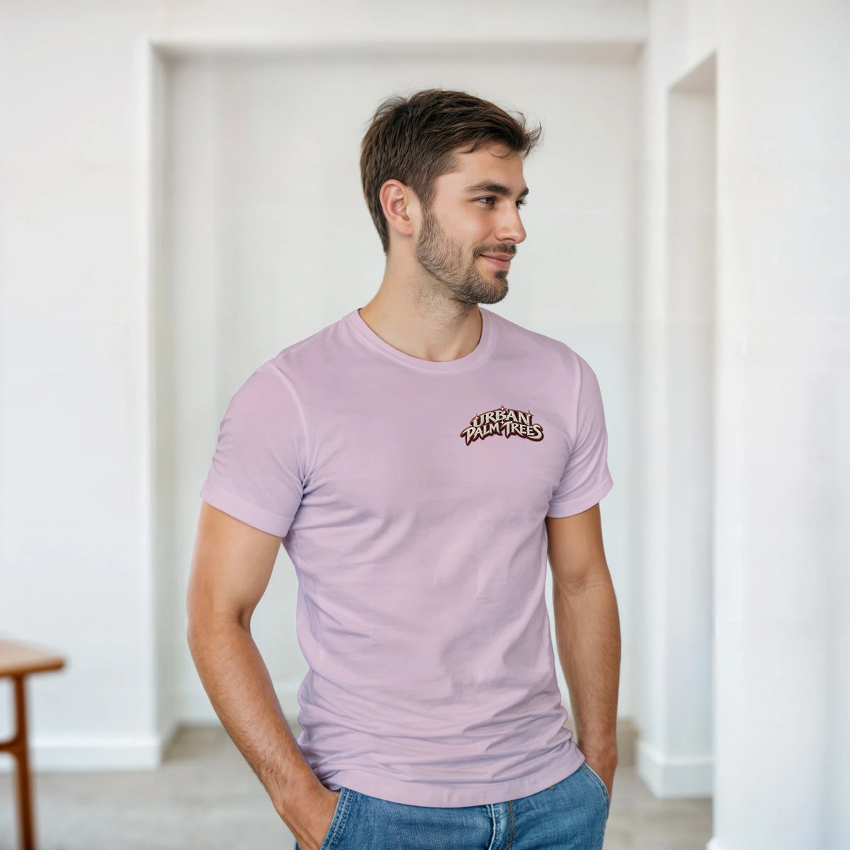 Man wearing a light purple crew-neck t-shirt with a small retro "Urban Palm Trees" logo on the chest, styled with blue jeans.