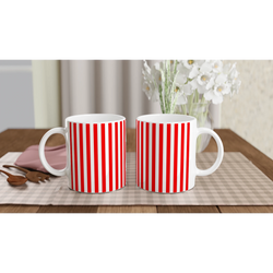 Two red-striped ceramic mugs with retro candy cane design on a table, white flowers in the background.