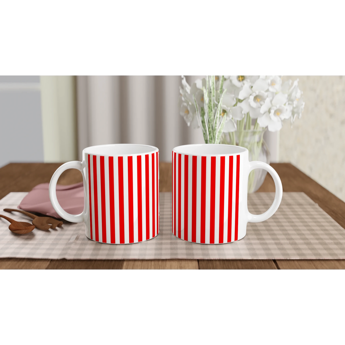 Two red-striped ceramic mugs with retro candy cane design on a table, white flowers in the background.