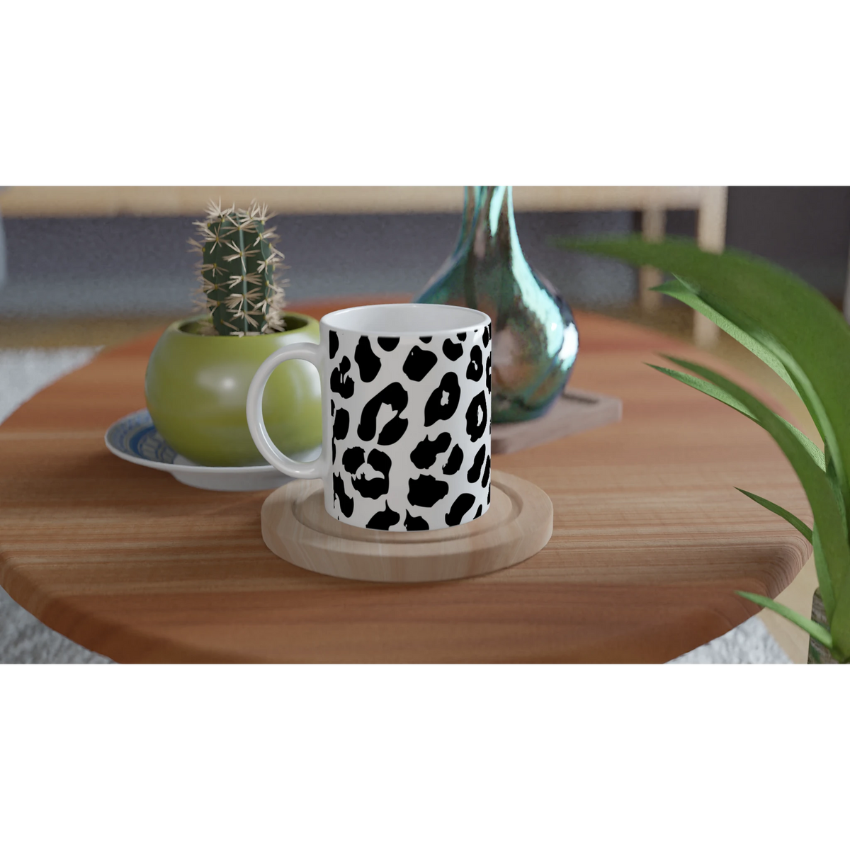 Retro Snow Leopard Mug with black leopard spots on white ceramic, on wooden table beside a cactus and green vase.