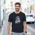 Gothic Glory men's graphic T-shirt in black with grayscale statue and 'Glory' script on urban street.