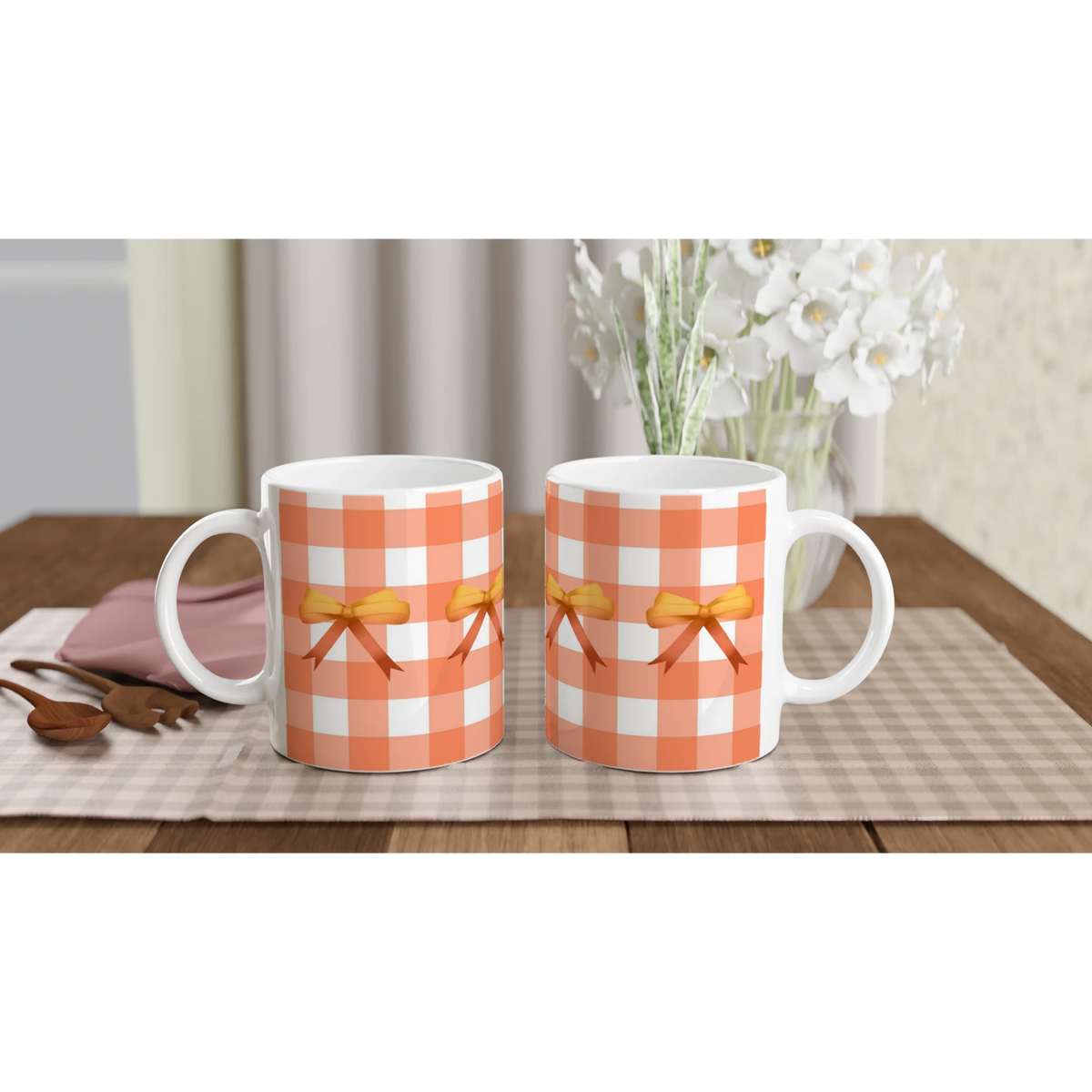 Orange gingham bow mugs with ribbons on a checkered table, white flowers in the background.