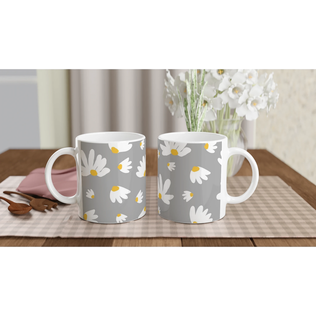 Ditsy Daisy mugs with white and yellow daisies on gray, placed on a checkered tablecloth.
