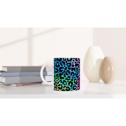Rainbow leopard-print mug on a desk with notebooks.