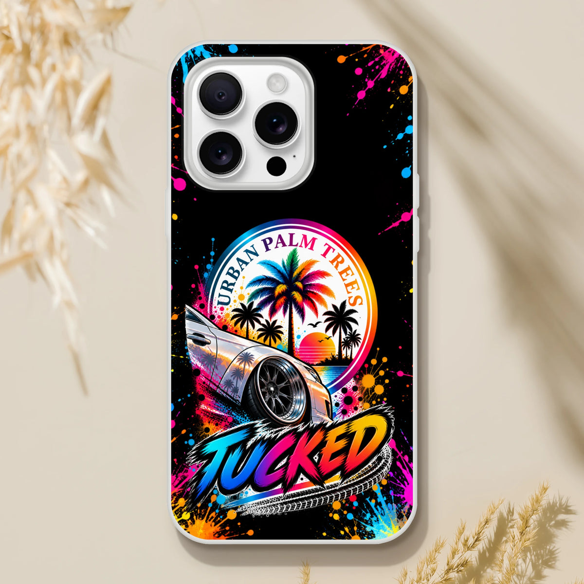 Tucked Stance iPhone case featuring lowered car graphic, colorful splatter art, and Urban Palm Trees sunset design for petrolheads.