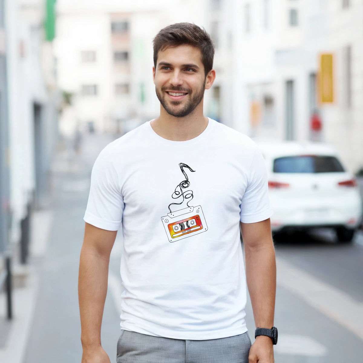 White men's t-shirt featuring a retro cassette tape graphic with unspooling tape and "80s Hits" text for nostalgic streetwear.