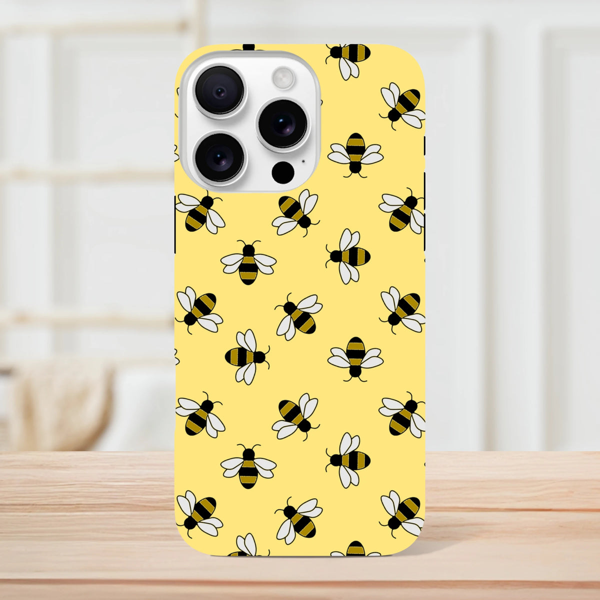 Yellow iPhone case featuring a cute repeating bumble bee pattern on a bright background, offering tough protection for iPhone 13-16 models.
