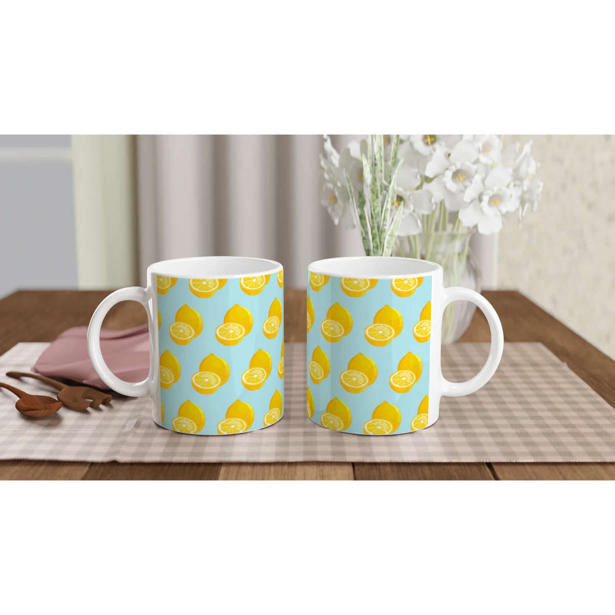 Pastel blue ceramic mugs with yellow lemon print pattern on checkered table mat