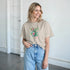 Beige Paradise women's graphic T-shirt with tropical floral print worn by a smiling model.