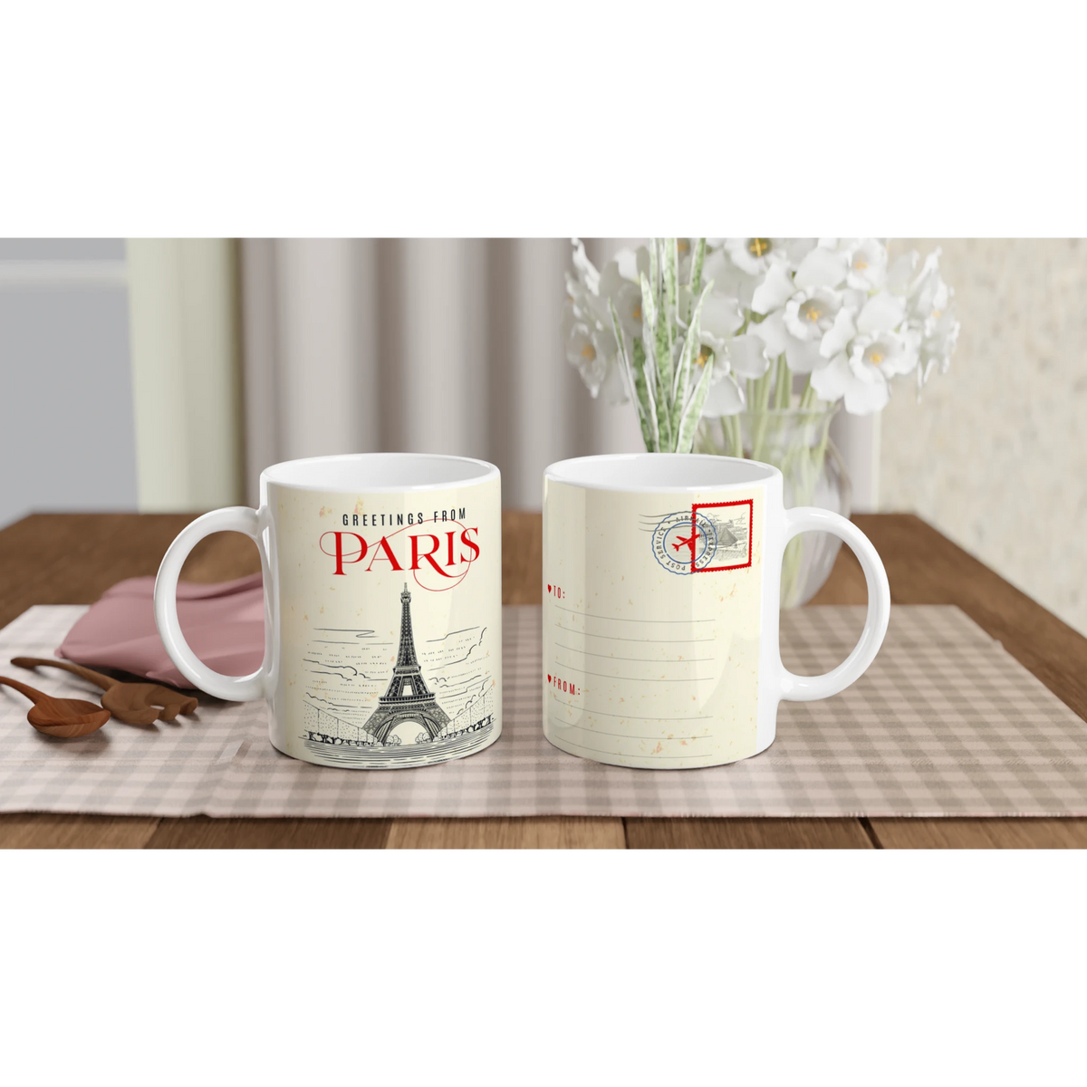 Two Vintage Paris mugs featuring postcard designs and Eiffel Tower motifs on a checkered table with flowers.