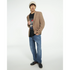 Male model wearing tan blazer, black graphic T-shirt, blue jeans, and beige beanie.
