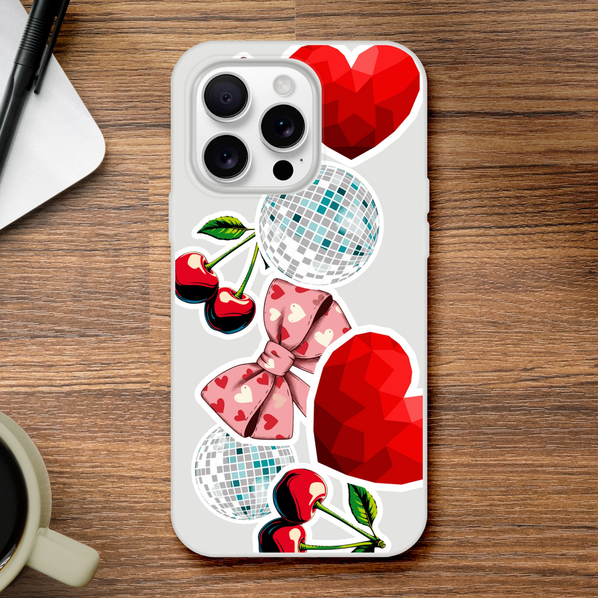 Transparent iPhone case with Y2K sticker art featuring red cherries, pink heart bows, disco balls, and faceted red hearts on a glossy shell.