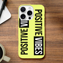 Yellow Tough iPhone Case featuring bold vertical "POSITIVE VIBES" slogan print in black and white on a wood desk.