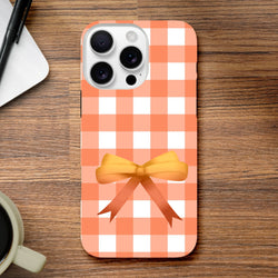 Impact-resistant orange gingham iPhone case featuring a cute yellow coquette bow design for sturdy daily protection.