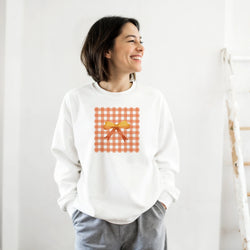 White sweatshirt featuring an orange gingham square graphic with a yellow coquette bow, perfect for cute street-style layering.