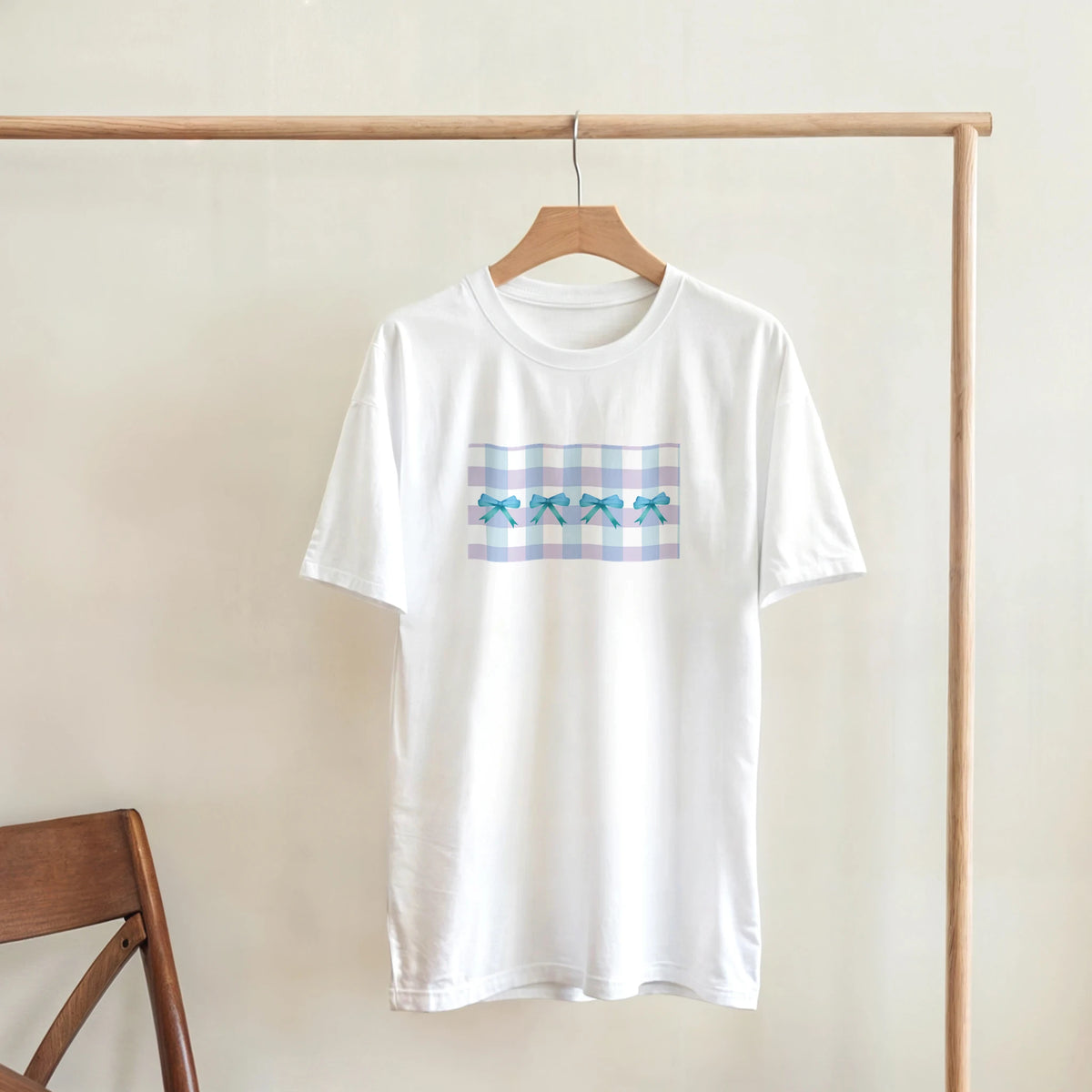 White T-shirt on a wooden hanger with pastel blue bow gingham print, Coquette aesthetic tee.