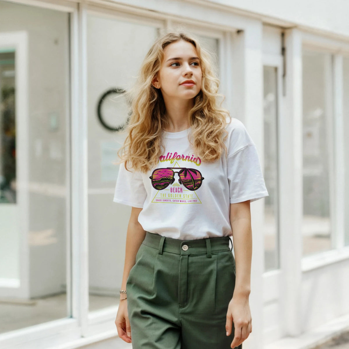 Woman wearing a white Y2K California Beach T‑Shirt with retro sunglasses graphic.