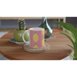 Pink lemon-pattern ceramic mug on a wooden table with a cactus and greenery in the background.