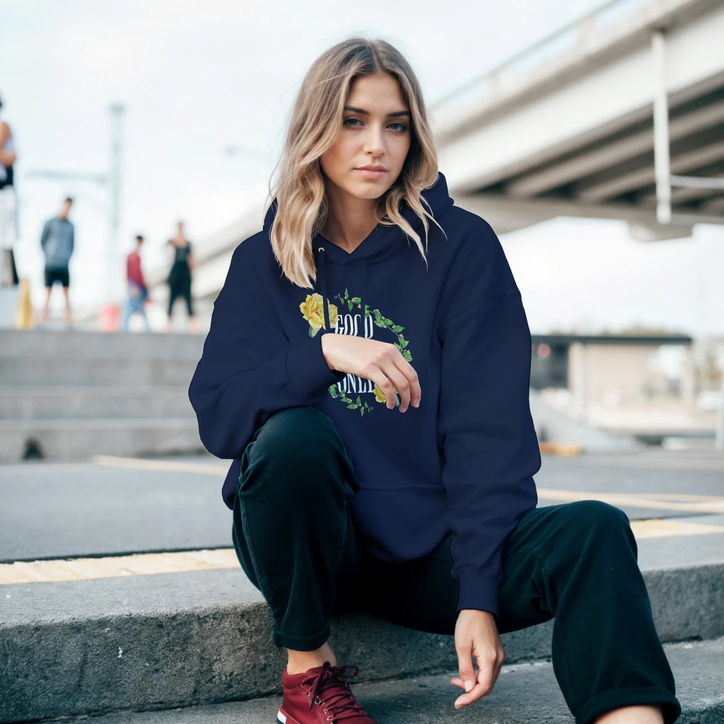 Woman wearing navy Good Vibes Only hoodie, soft 50/50 cotton blend, floral wreath graphic, front pouch pocket.