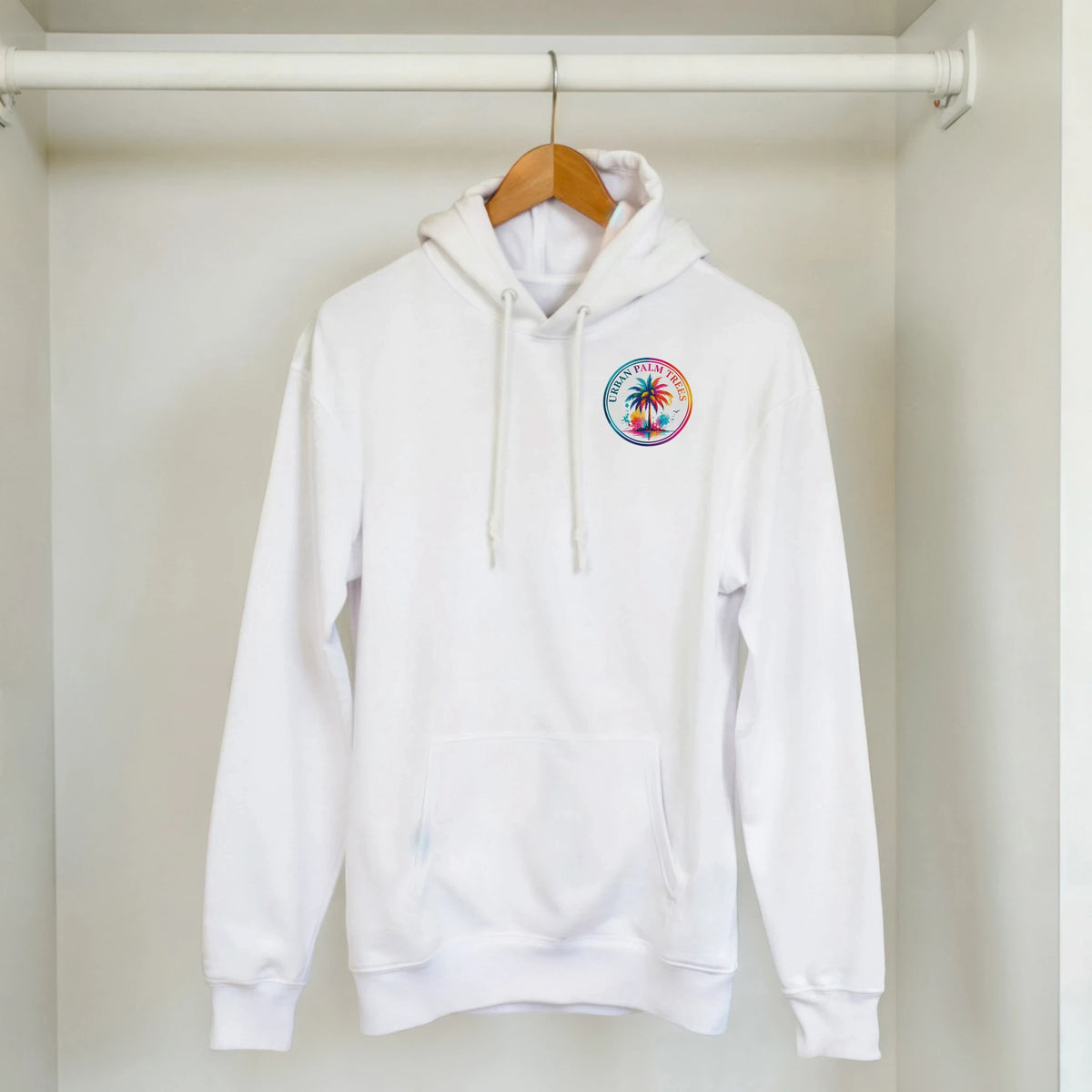 White hoodie featuring a colorful circular palm tree graphic on the chest. Tropical retro streetwear top with matching drawstrings and kangaroo pocket.