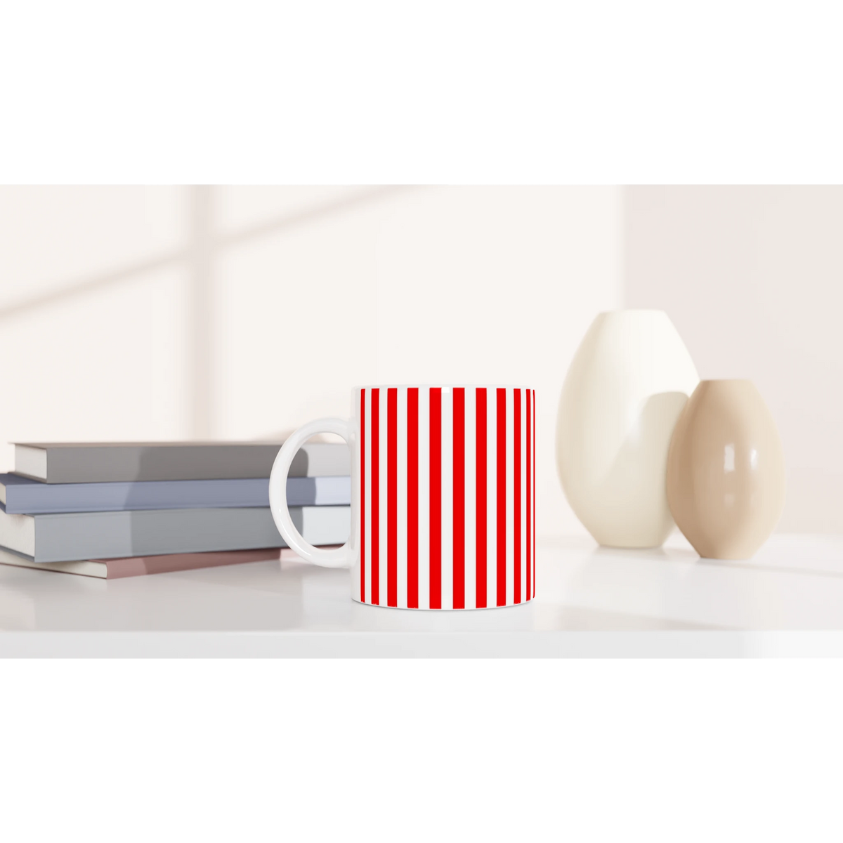 Red-striped ceramic mug with candy-cane pattern on a white desk beside stacked books.