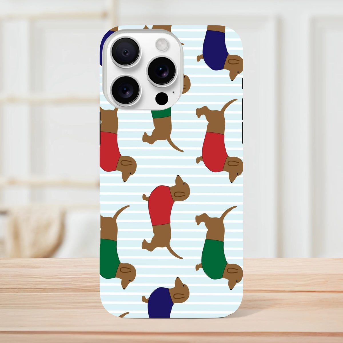 Cute Dachshund iPhone case featuring a playful sausage dog pattern in red and green sweaters on blue stripes. Tough phone cover.