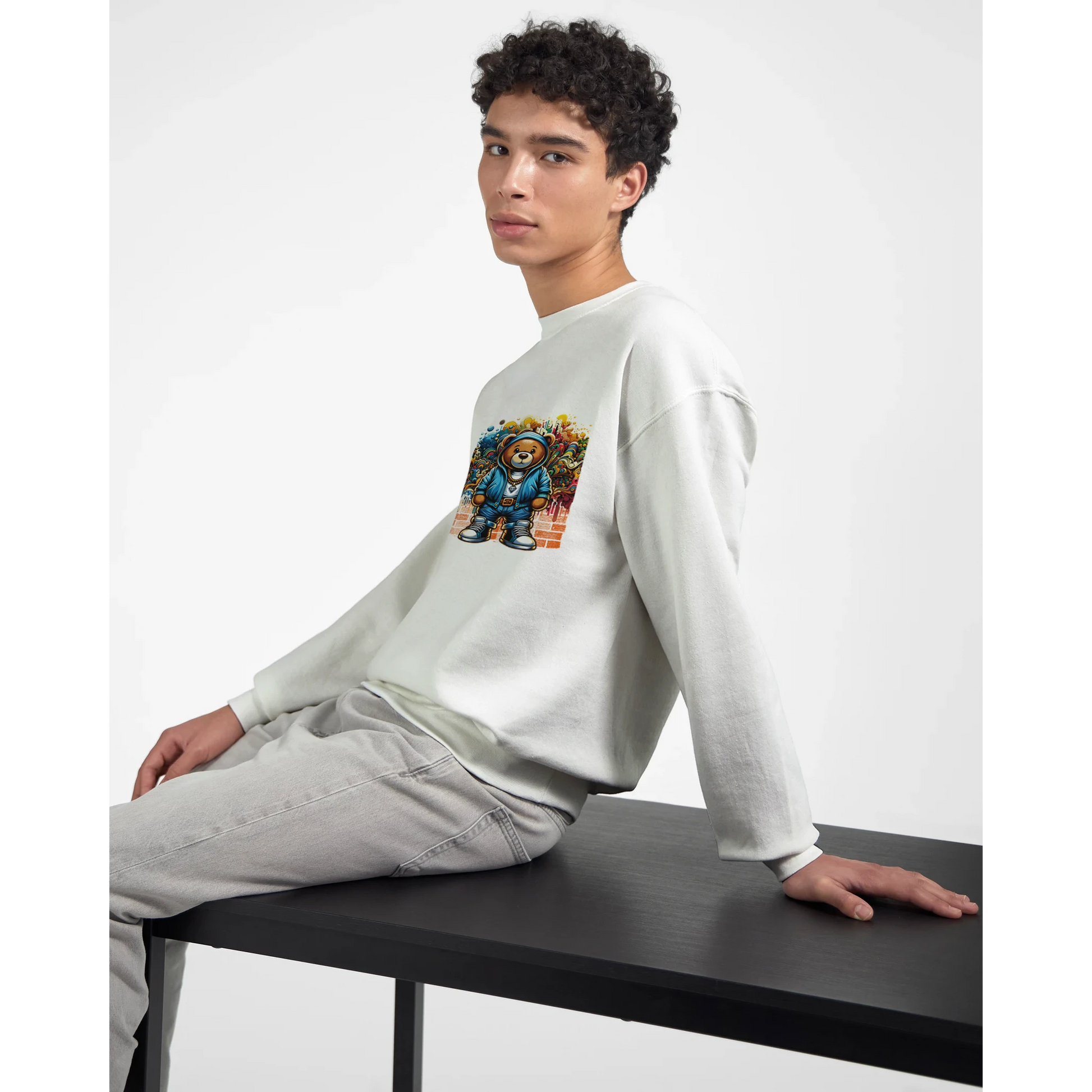 Person wearing a white men's graphic sweatshirt with a colorful graphic design sitting on a black table.