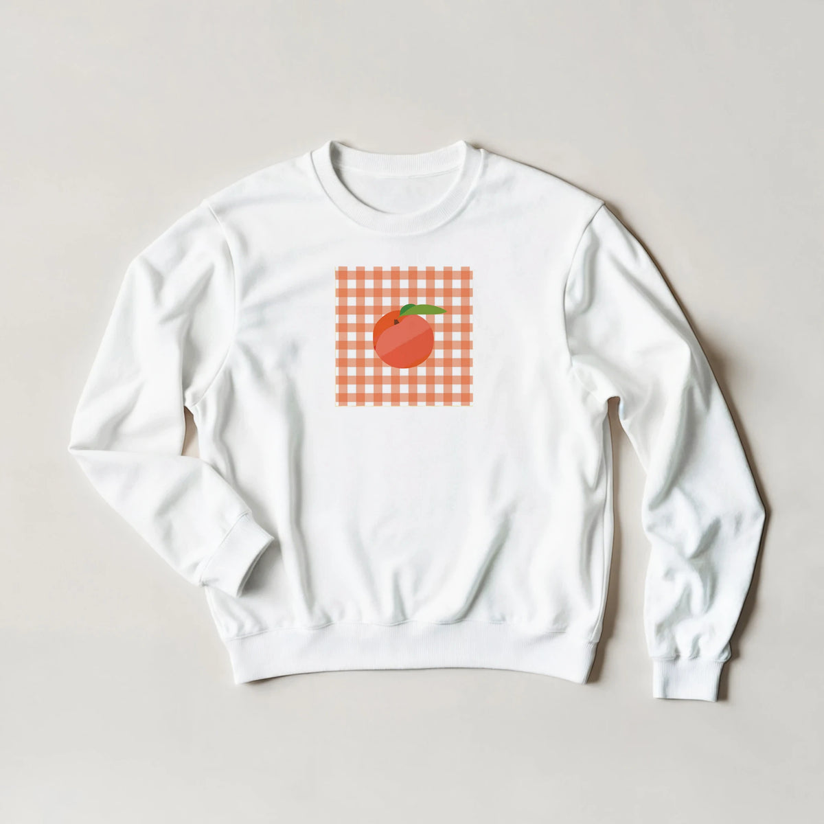 White sweatshirt with orange gingham square and peach graphic.