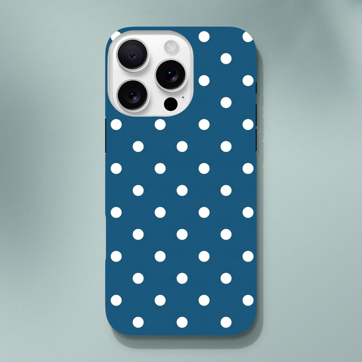 Navy blue tough iPhone case with white polka dots. Shock-absorbing dual-layer shell with gloss finish for iPhone 13-16.