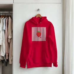 Red pullover hoodie featuring a retro strawberry graphic on a gingham square background. Vintage fruit design for women.