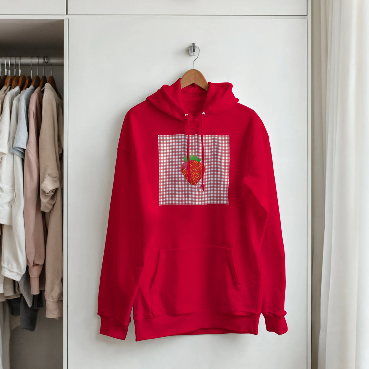 Red pullover hoodie featuring a retro strawberry graphic on a gingham square background. Vintage fruit design for women.