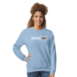 Woman in light-blue sweatshirt with POSITIVE VIBES slogan, casual streetwear style.