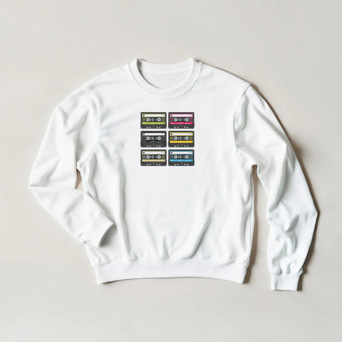 White sweatshirt featuring a grid of six colorful retro cassette tape prints, capturing vintage 90s music nostalgia.