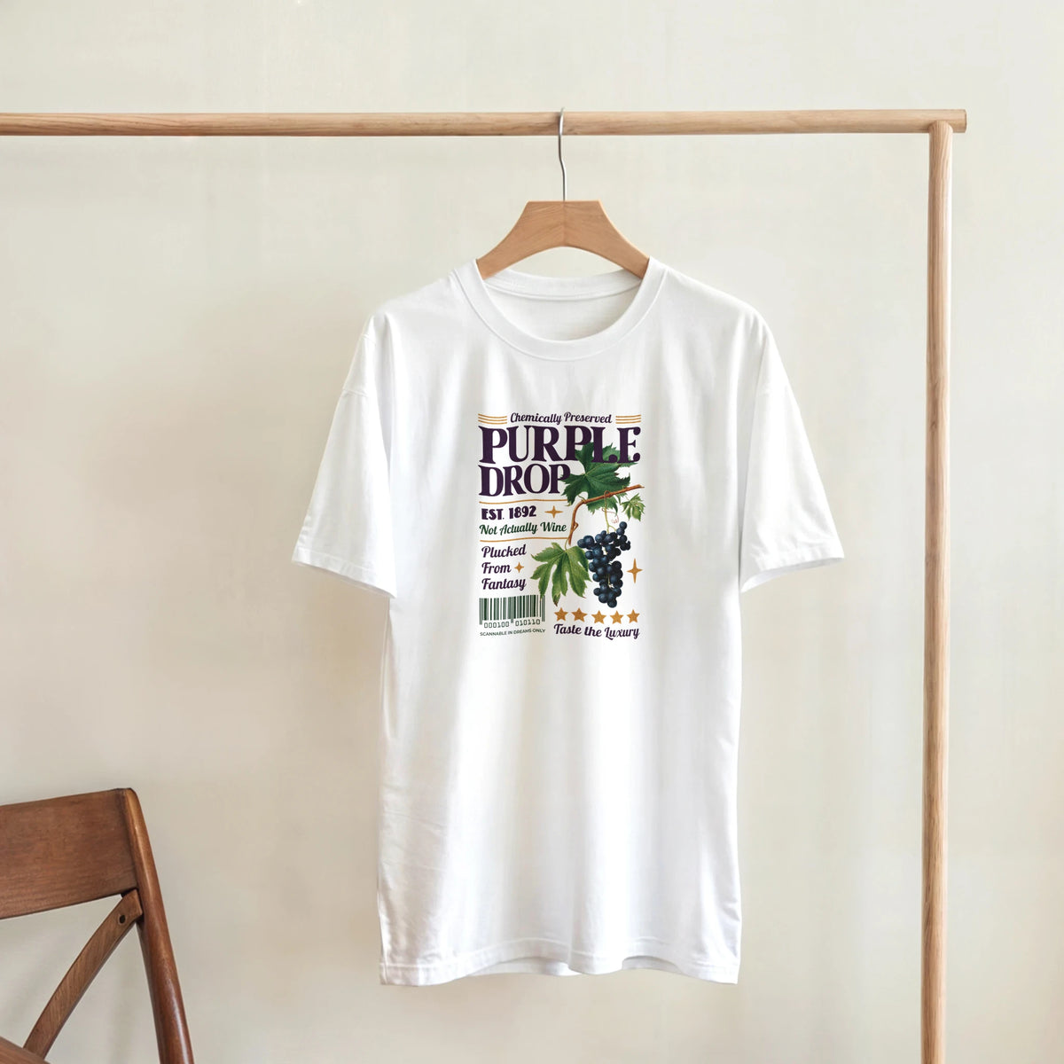 White vintage purple grape graphic T-shirt on a wooden hanger, retro fruit tee design.